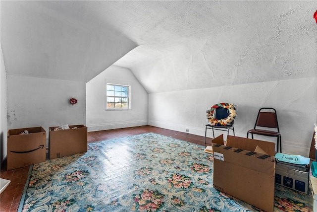 additional living space with hardwood / wood-style flooring, lofted ceiling, and a textured ceiling