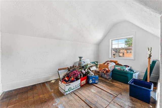 additional living space with a textured ceiling, lofted ceiling, and dark wood-type flooring