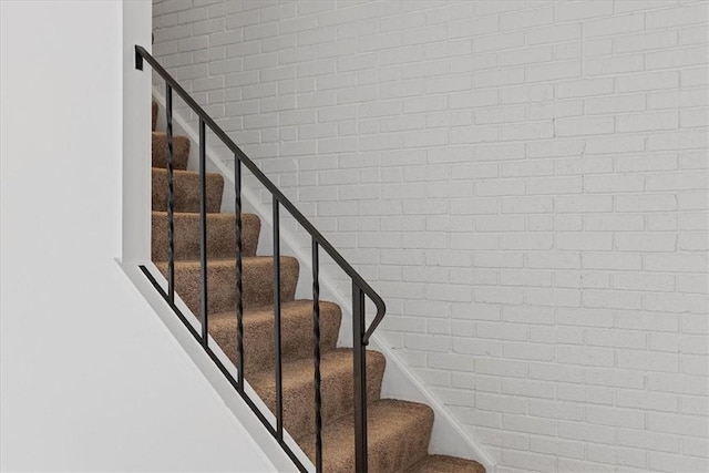 staircase featuring brick wall