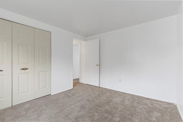 unfurnished bedroom with light carpet and a closet