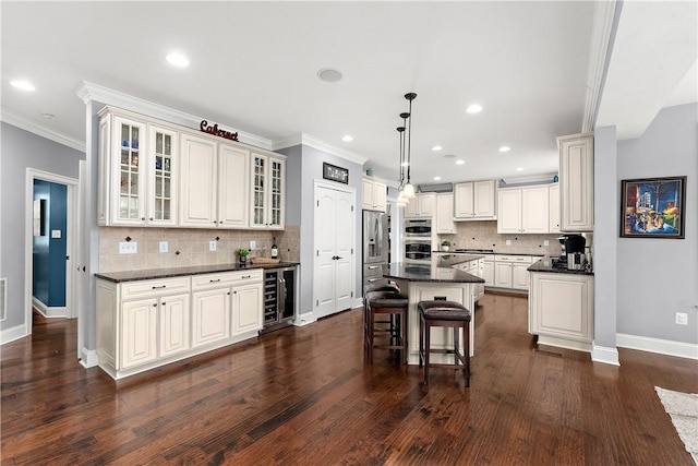 kitchen featuring a breakfast bar area, beverage cooler, backsplash, hanging light fixtures, and a center island