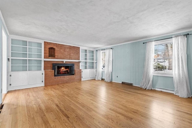 unfurnished living room featuring built in shelves, a baseboard radiator, light hardwood / wood-style flooring, and a brick fireplace