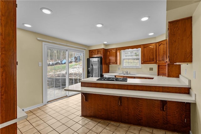 kitchen with sink, stainless steel appliances, kitchen peninsula, a kitchen bar, and light tile patterned flooring