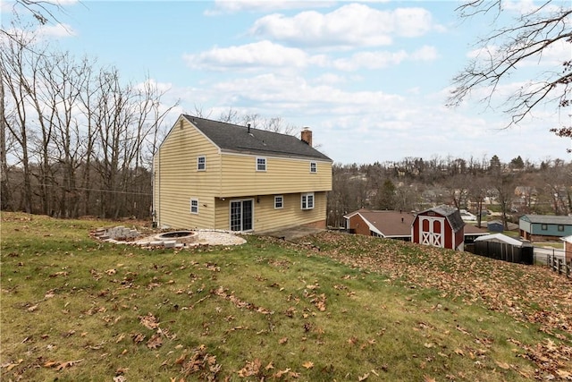 back of house featuring a storage shed and a yard