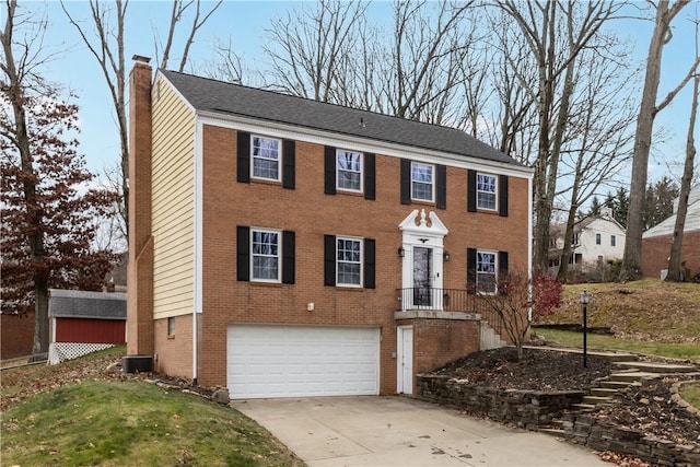 colonial home featuring central air condition unit and a garage