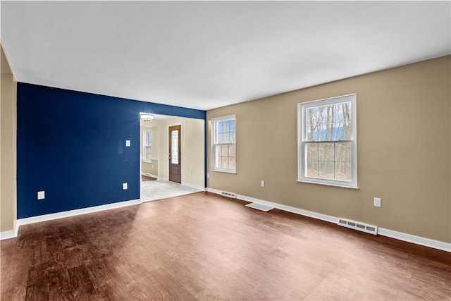 empty room with hardwood / wood-style flooring and an inviting chandelier