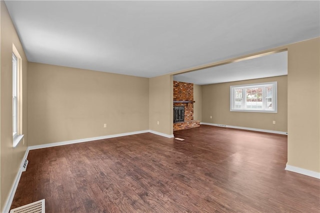 unfurnished living room featuring dark hardwood / wood-style floors and a brick fireplace