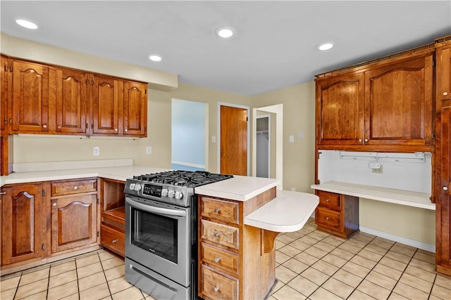 kitchen with kitchen peninsula, gas range, and light tile patterned flooring