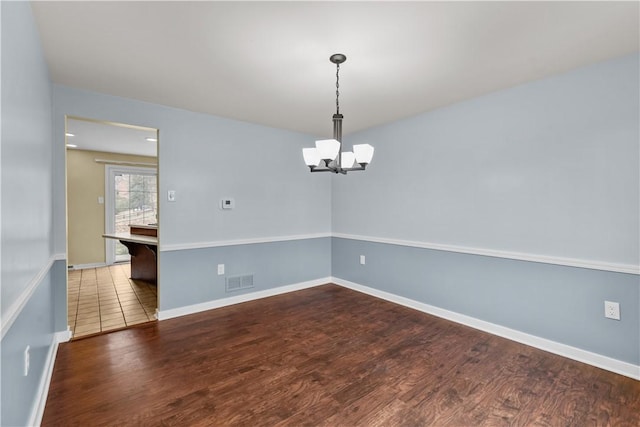 empty room featuring a notable chandelier and hardwood / wood-style flooring