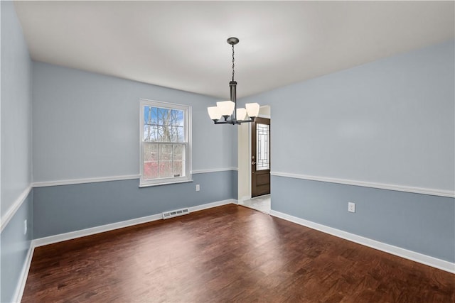 spare room with hardwood / wood-style flooring and a notable chandelier