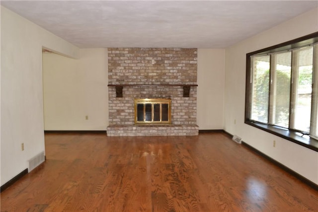 unfurnished living room with dark wood-type flooring and a brick fireplace