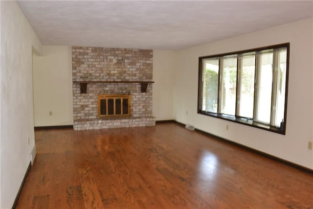 unfurnished living room with dark hardwood / wood-style floors and a brick fireplace