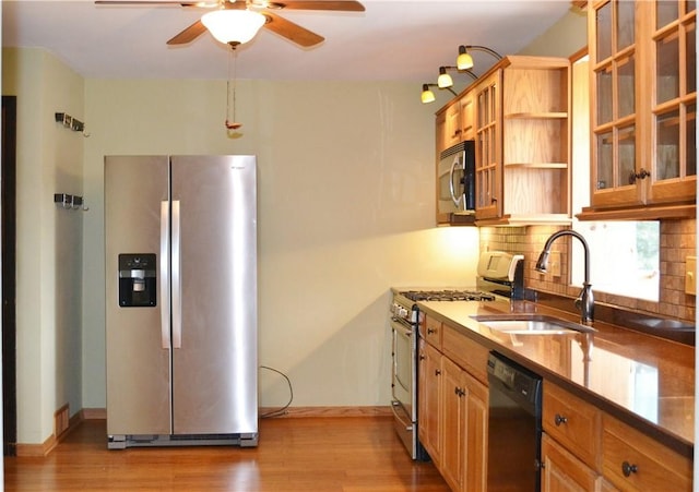 kitchen featuring decorative backsplash, appliances with stainless steel finishes, light wood-type flooring, ceiling fan, and sink