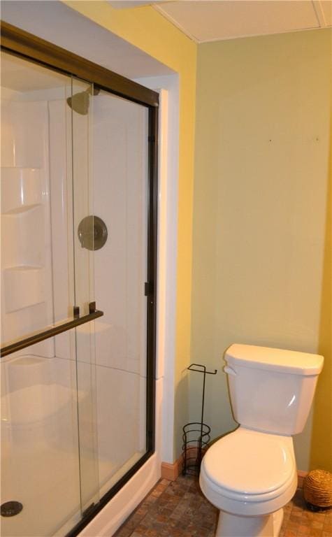 bathroom featuring a shower with shower door and toilet