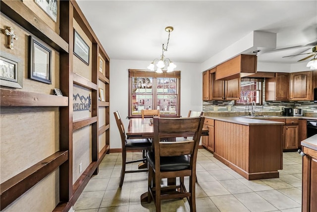 kitchen featuring backsplash, ceiling fan with notable chandelier, sink, light tile patterned floors, and decorative light fixtures