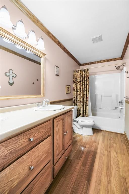 full bathroom with hardwood / wood-style floors, vanity, shower / bathtub combination with curtain, and crown molding