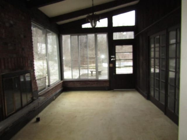 sunroom / solarium featuring vaulted ceiling with beams