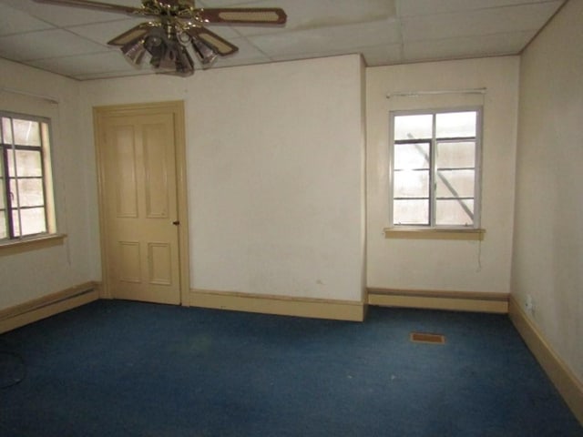 unfurnished room with ceiling fan, a drop ceiling, a baseboard radiator, and dark colored carpet