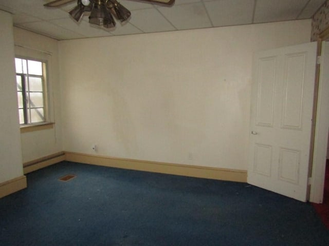 spare room featuring ceiling fan, a drop ceiling, a baseboard heating unit, and dark colored carpet