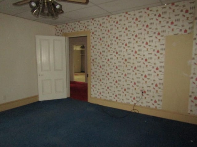 carpeted empty room featuring a drop ceiling and ceiling fan