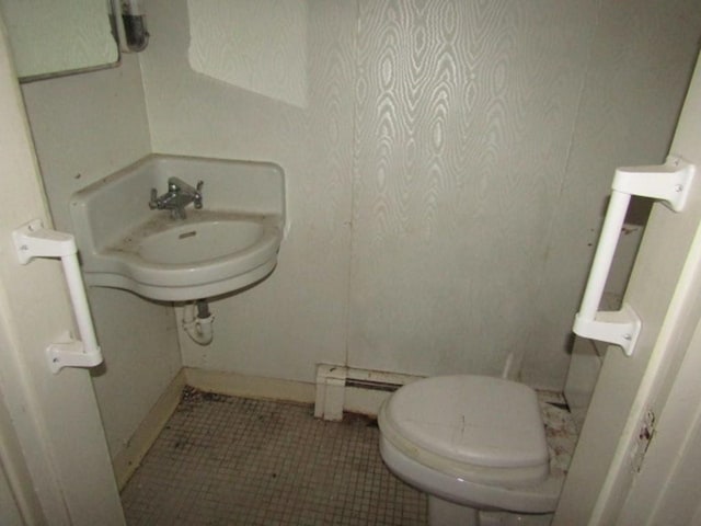 bathroom with baseboard heating, sink, tile patterned flooring, and toilet