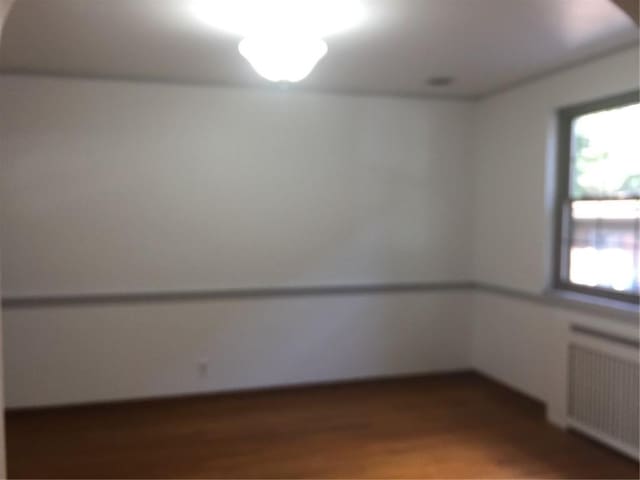 empty room featuring hardwood / wood-style flooring and radiator