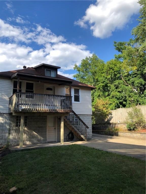 rear view of house with a wooden deck and a lawn