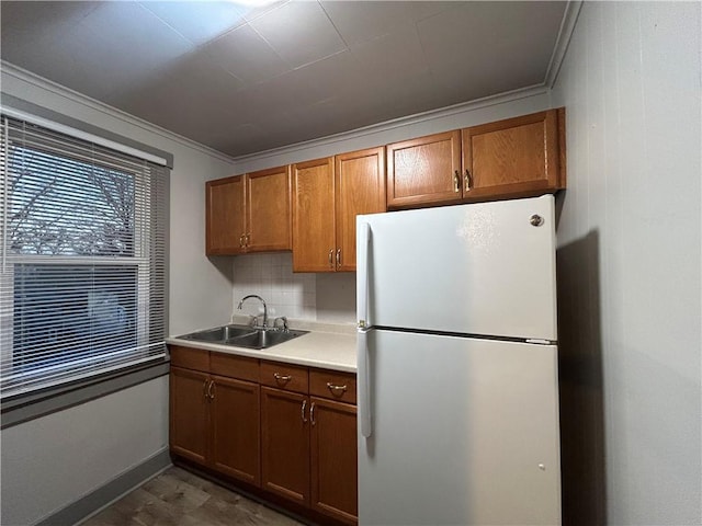 kitchen featuring tasteful backsplash, ornamental molding, white fridge, and sink