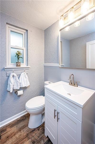 bathroom with vanity, toilet, wood-type flooring, and a textured ceiling