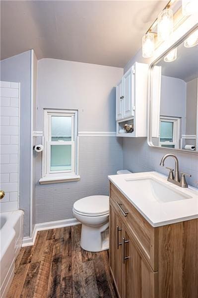 bathroom with vanity, toilet, wood-type flooring, and tile walls