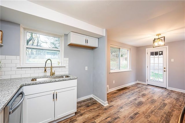 kitchen with decorative backsplash, light stone counters, stainless steel dishwasher, sink, and white cabinets