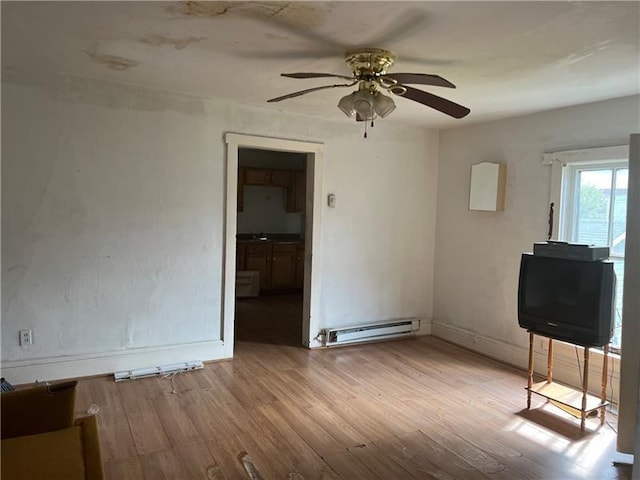 empty room with ceiling fan, light wood-type flooring, sink, and a baseboard heating unit