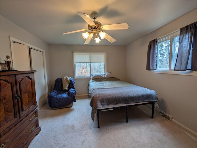 carpeted bedroom with ceiling fan, a closet, and multiple windows