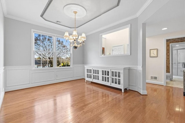 unfurnished dining area featuring a notable chandelier, crown molding, and light hardwood / wood-style flooring