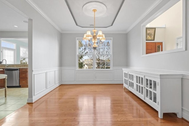 dining room featuring ornamental molding, light wood-type flooring, a notable chandelier, and sink