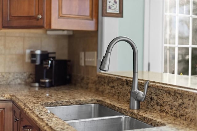 kitchen with tasteful backsplash, light stone counters, and sink