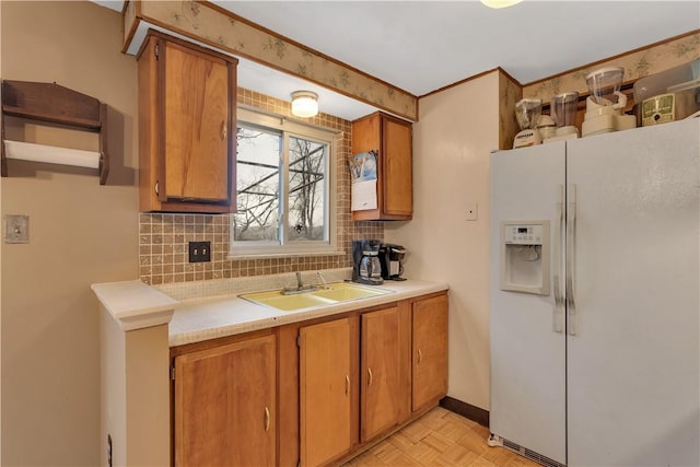 kitchen with white refrigerator with ice dispenser, backsplash, light parquet floors, and sink