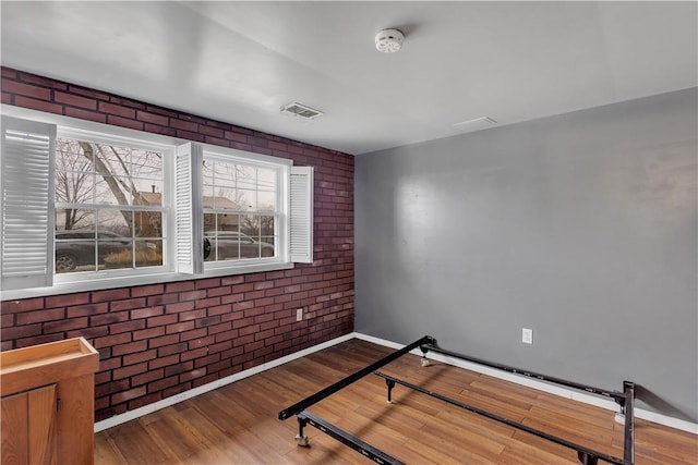 interior space with hardwood / wood-style flooring and brick wall