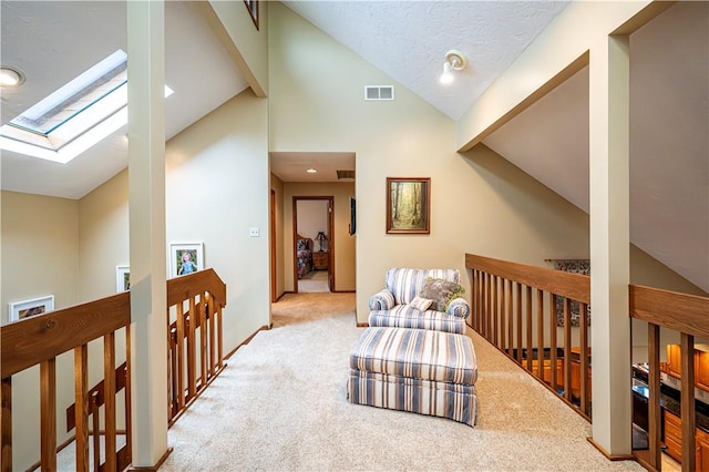 interior space featuring vaulted ceiling with skylight, light colored carpet, and a textured ceiling