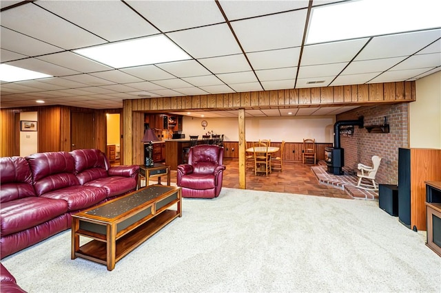 carpeted living room featuring a wood stove and wood walls