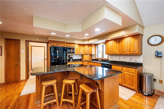 kitchen featuring a kitchen breakfast bar, a center island, black appliances, and light hardwood / wood-style floors