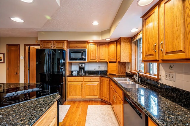 kitchen with sink, backsplash, dark stone countertops, and black appliances