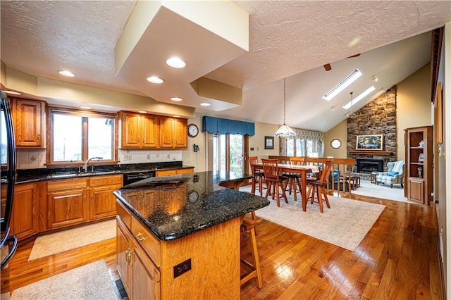 kitchen with a kitchen breakfast bar, light wood-type flooring, a skylight, a fireplace, and a kitchen island