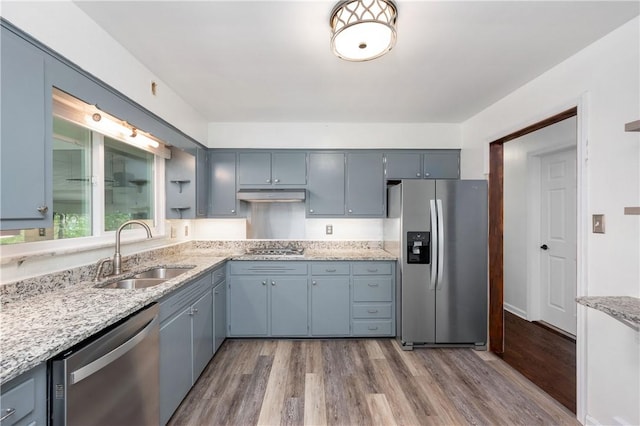 kitchen featuring light stone counters, sink, stainless steel appliances, and light wood-type flooring