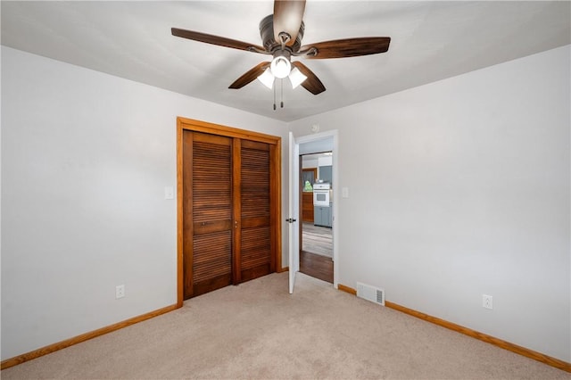 unfurnished bedroom featuring light carpet, a closet, and ceiling fan