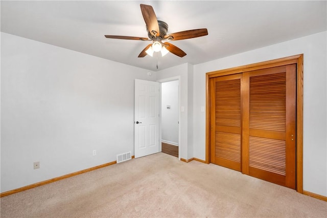 unfurnished bedroom featuring ceiling fan, a closet, and light carpet