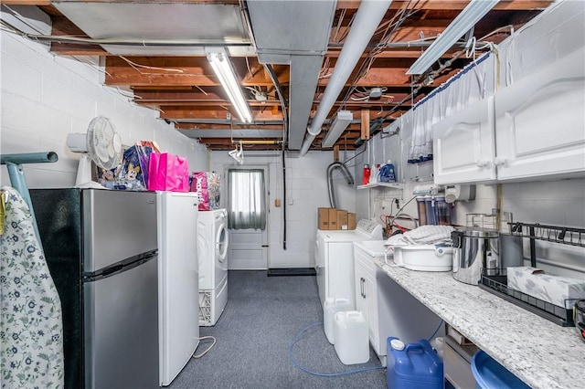 basement with stainless steel refrigerator and separate washer and dryer