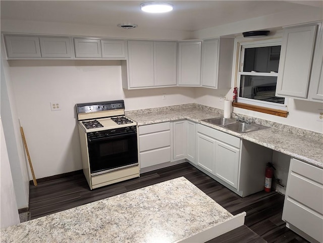 kitchen with sink, light stone counters, dark hardwood / wood-style floors, white range oven, and white cabinets