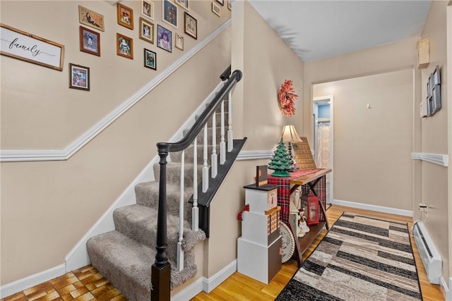 stairway featuring wood-type flooring and a baseboard radiator