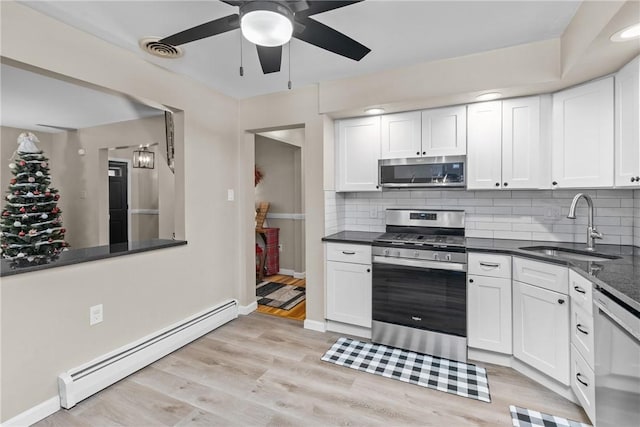 kitchen featuring a baseboard heating unit, sink, light hardwood / wood-style flooring, white cabinetry, and stainless steel appliances